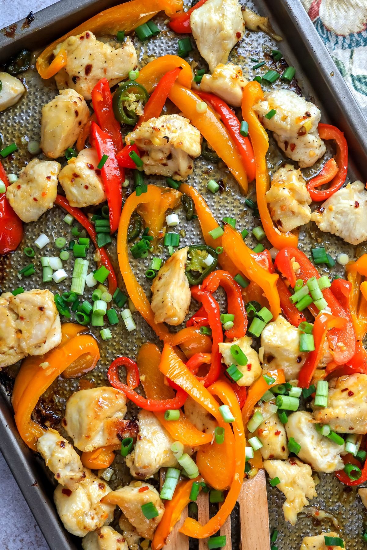 Sheet pan with vibrant peppers and cooked chicken on it. 