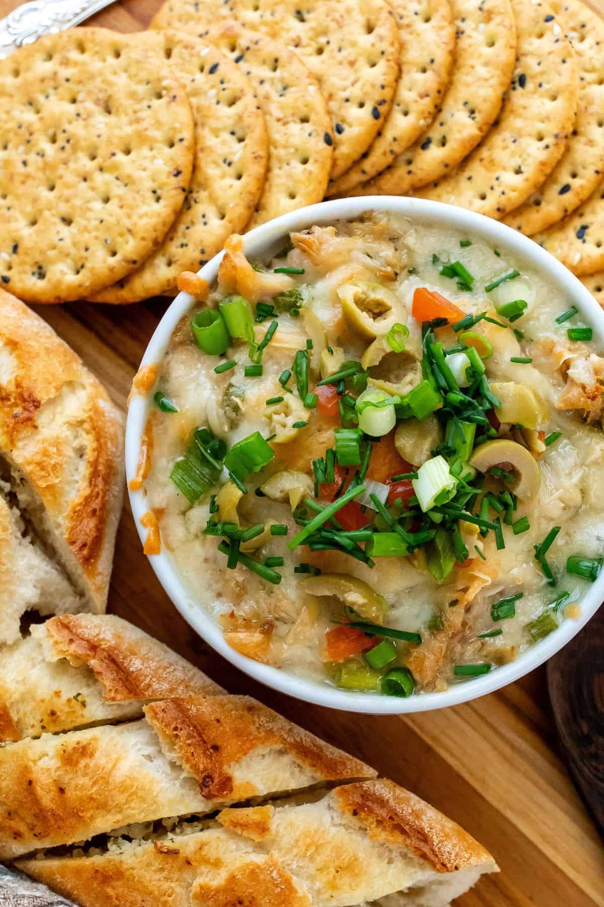 white ramekin with tuna dip and toppings up close with crackers on the side. 