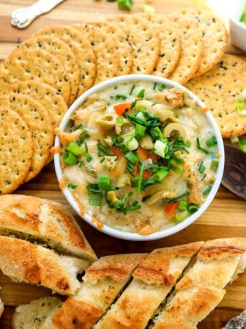 White ceramic bowl filled with tuna dip and topped with onions and chives.