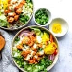 A grey bowl with buffalo sauce. Cucumber to the side with a ranch drizzle.