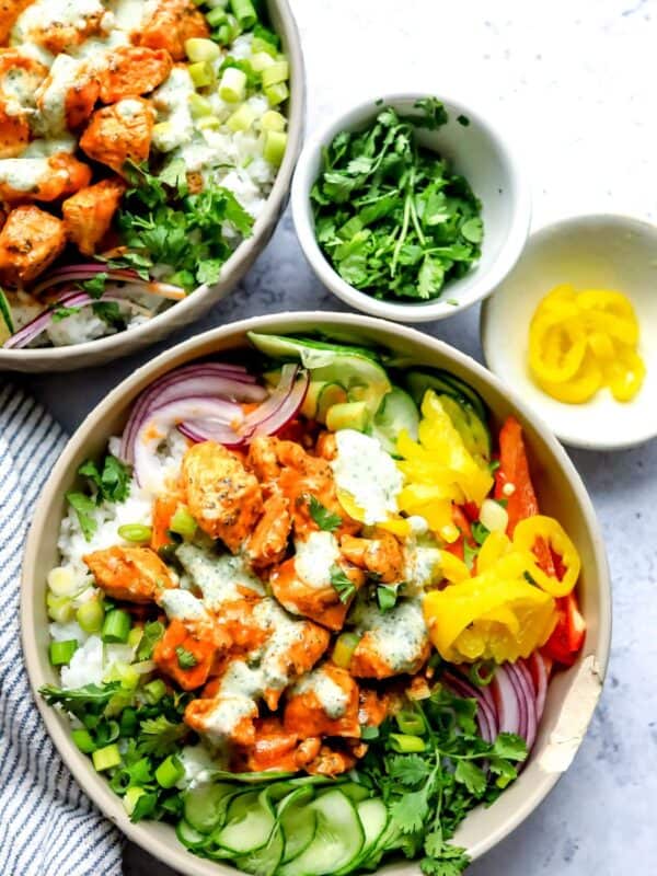 A grey bowl with buffalo sauce. Cucumber to the side with a ranch drizzle.