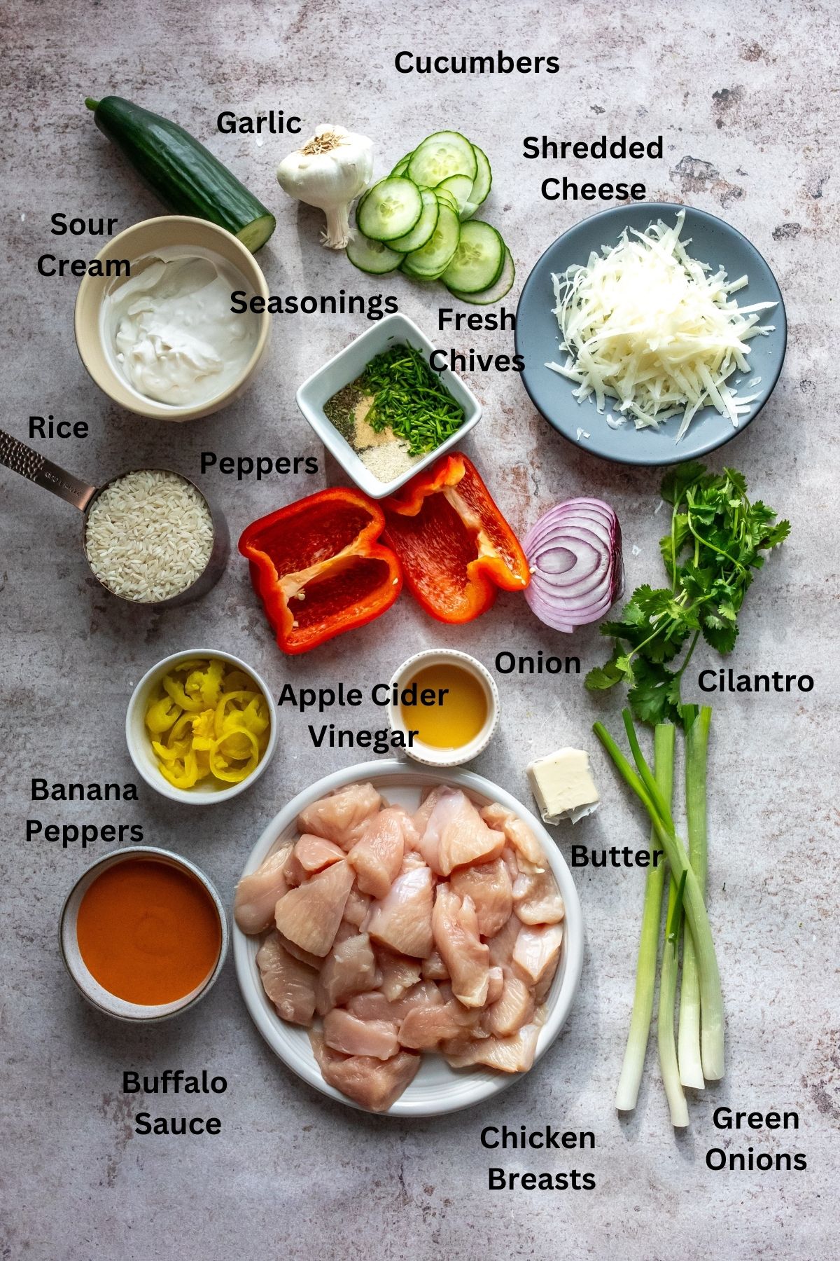 Ingredients needed on a counter. Cucumber, chicken and more on pates and small bowls. 