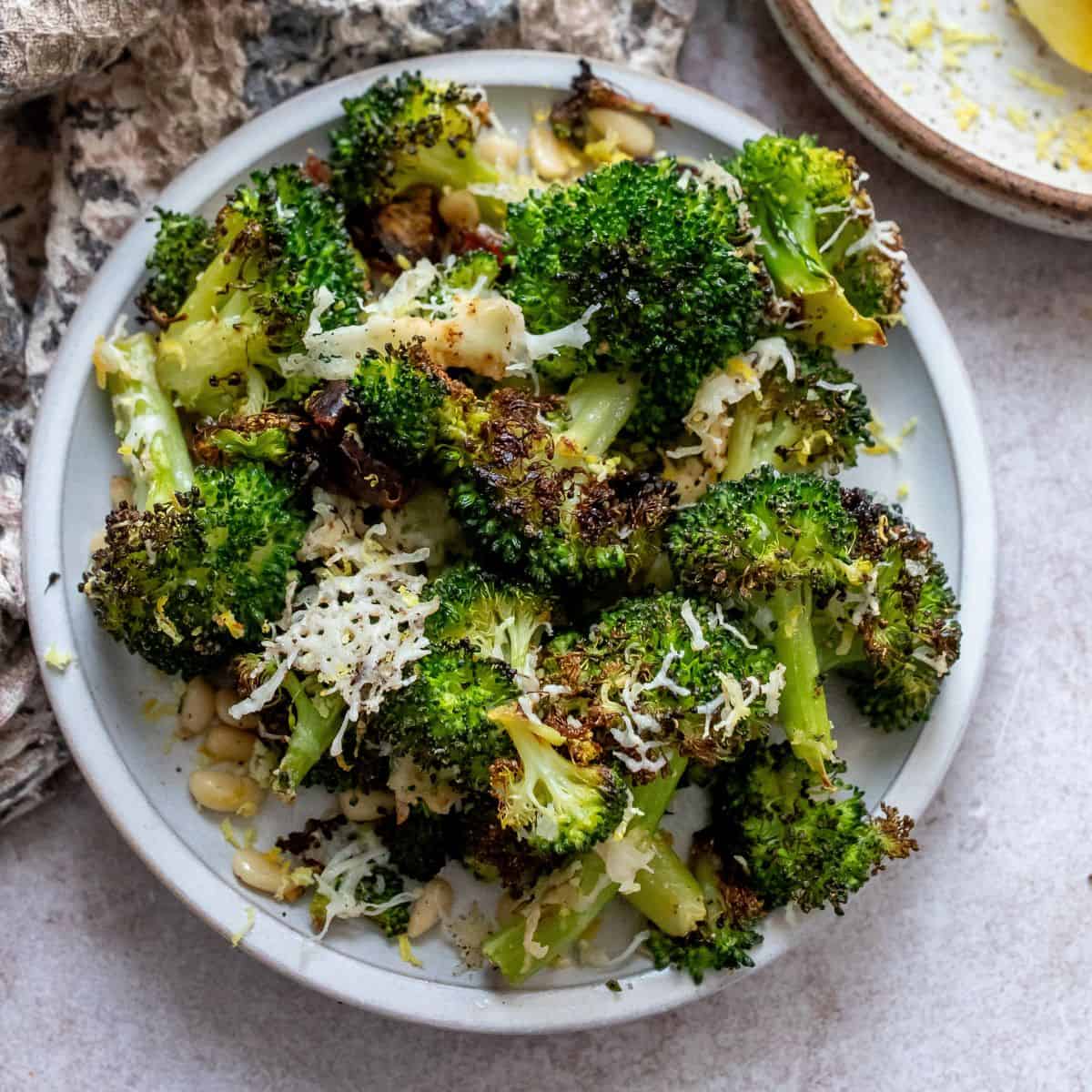 White bowl with charred broccoli and toppings mixed in.