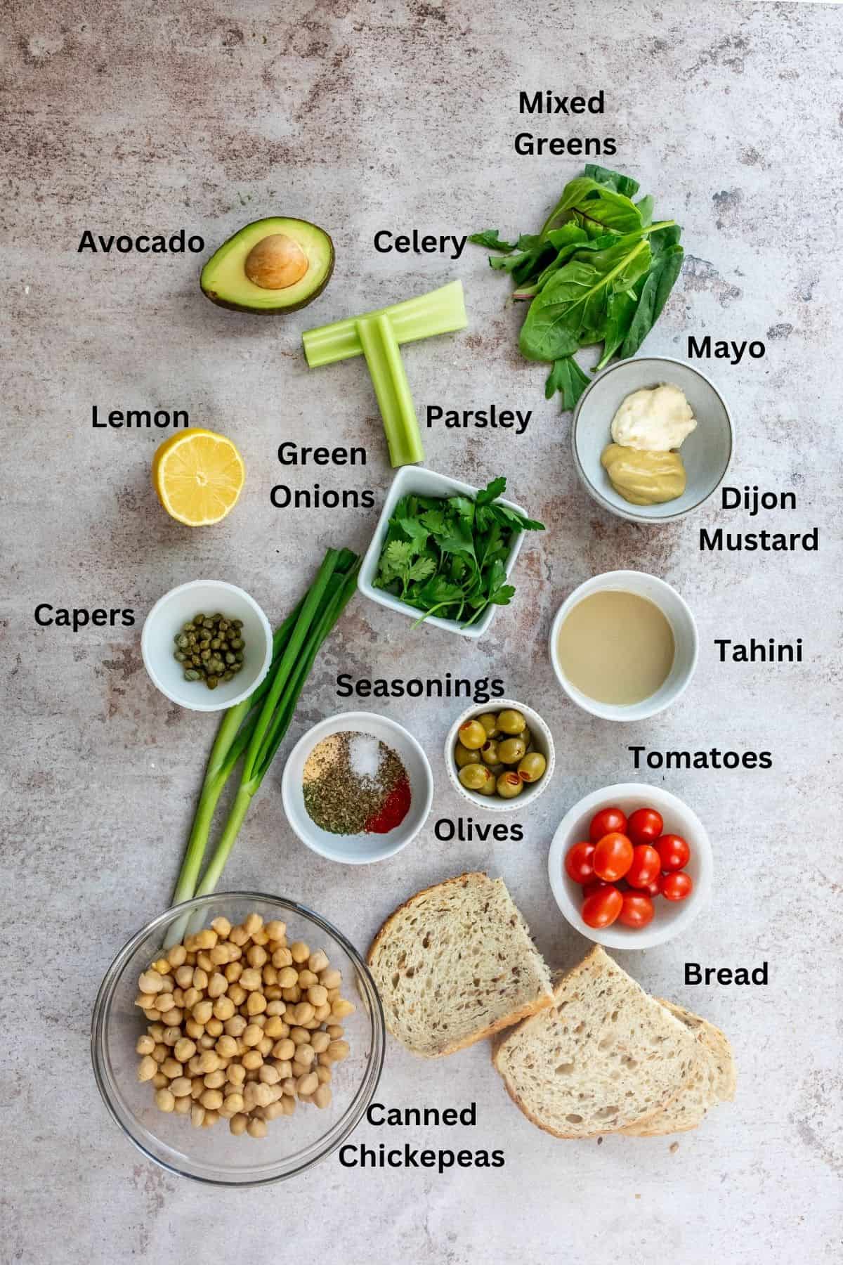 Ingredients needed to make this salad in small bowls and on a counter. 