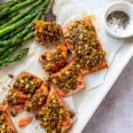 Salmon with pistachios baked on top with white parchment paper underneath