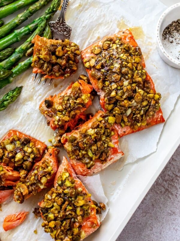 Salmon with pistachios baked on top with white parchment paper underneath