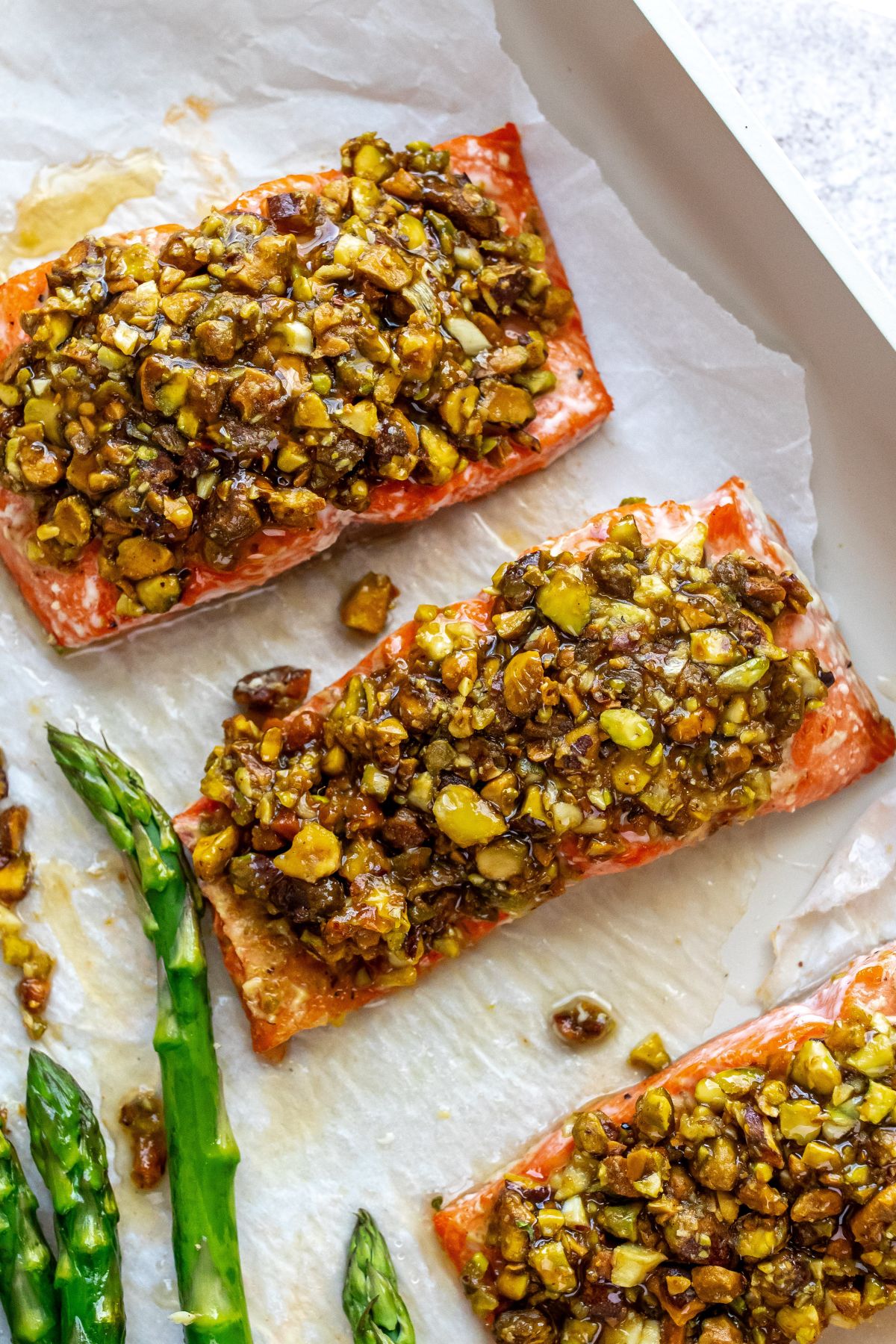 Salmon with pistachios on top up close on a baking tray. 