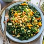 Grey plate with kale and peanuts. Dressing and fork on the side.