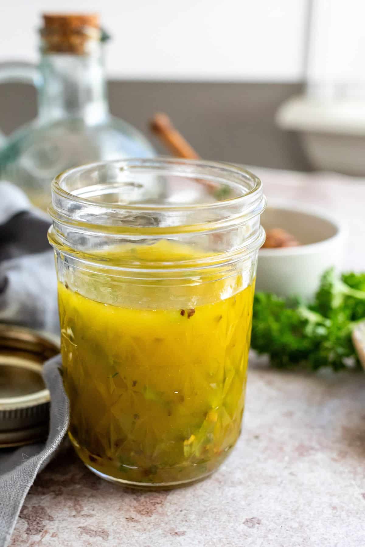 Glass jar with lemon honey dressing in it. Olive oil on the side. 
