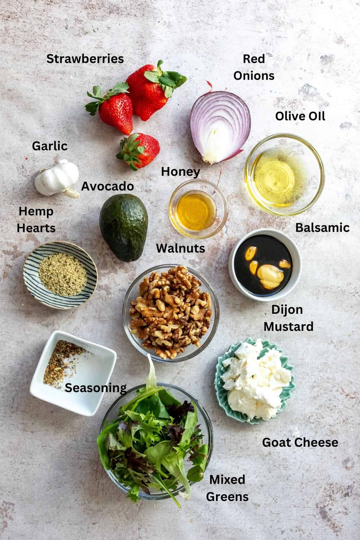 Ingredients to make Strawberry goat cheese salad on a counter in small bowls. 