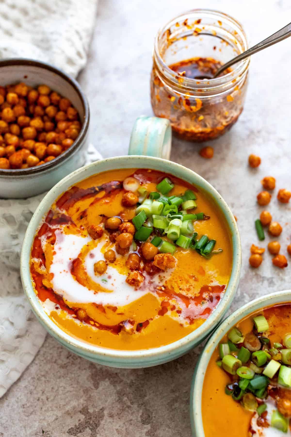 carrot lentil soup in a mug with chili crunch on top. 