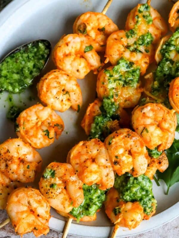Baked Shrimp Skewers on a white plate with sauce.