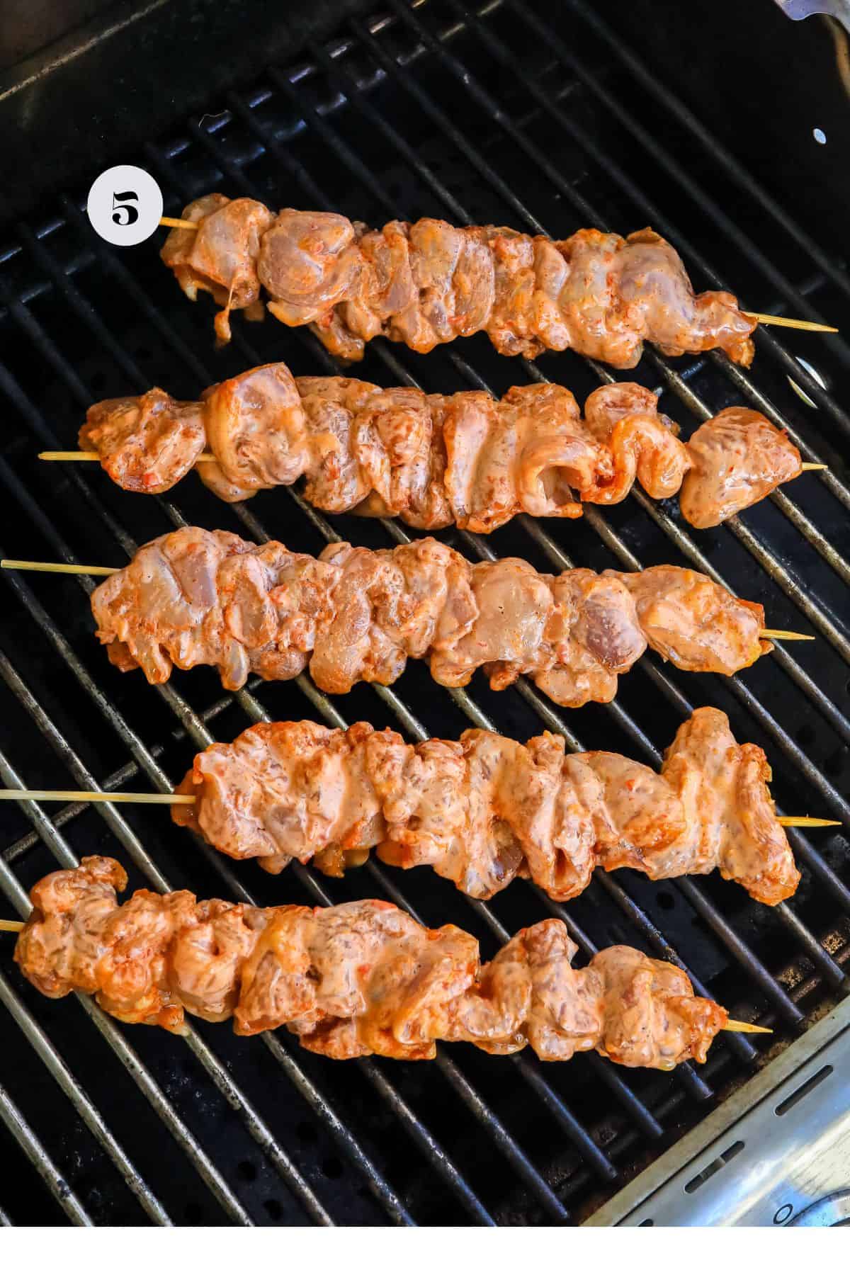 Grill with spicy chicken skewers on it with wooden sticks. 