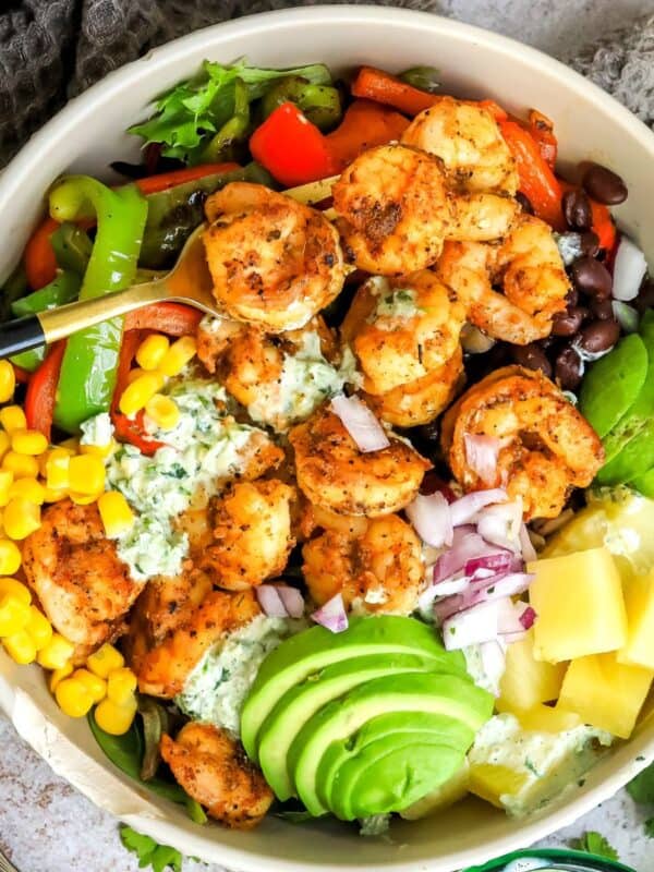 Grey bowls with salad and blackened shrimp. Gold fork to the side.