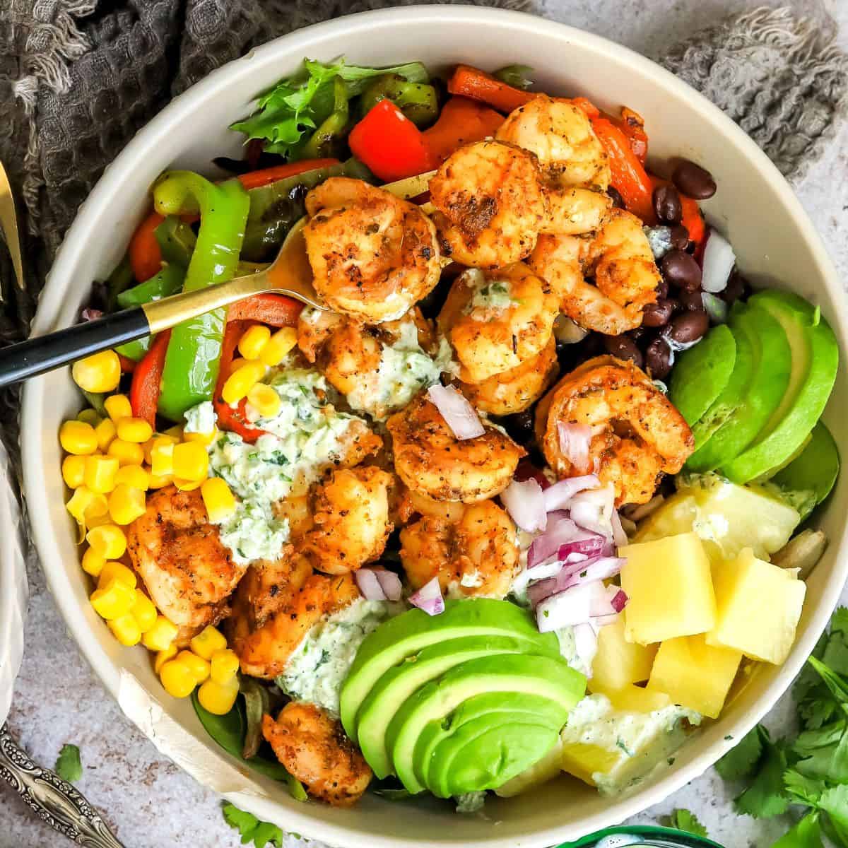 Grey bowls with salad and blackened shrimp. Gold fork to the side.