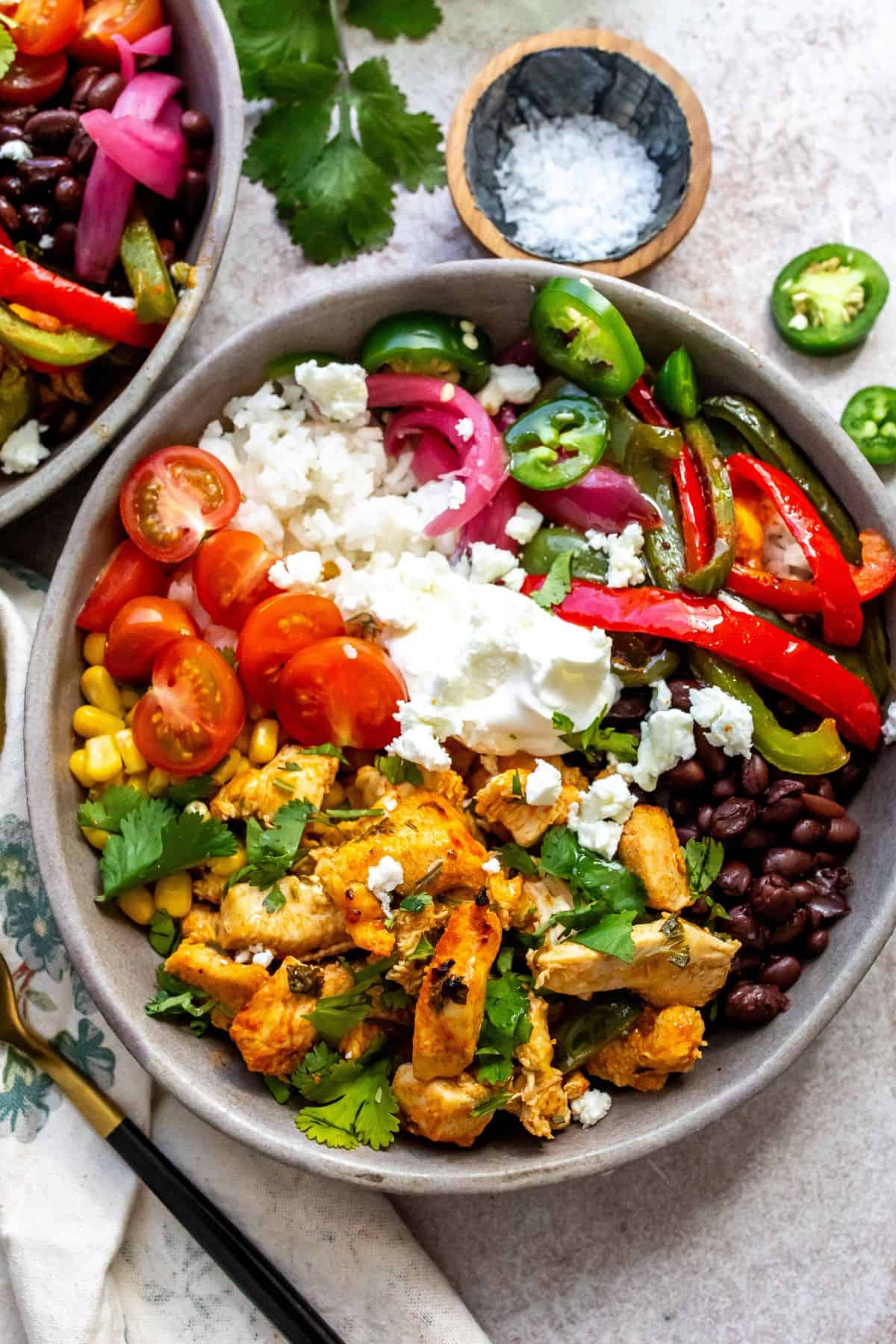 Grey ceramic bowls with cilantro lime chicken and lots of veggie toppings