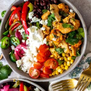 Grey ceramic bowls with cilantro lime chicken and lots of veggie toppings.