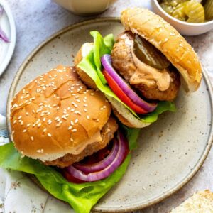 Air fryer spicy chicken burgers on a plate with a spoon of aioli to the side.