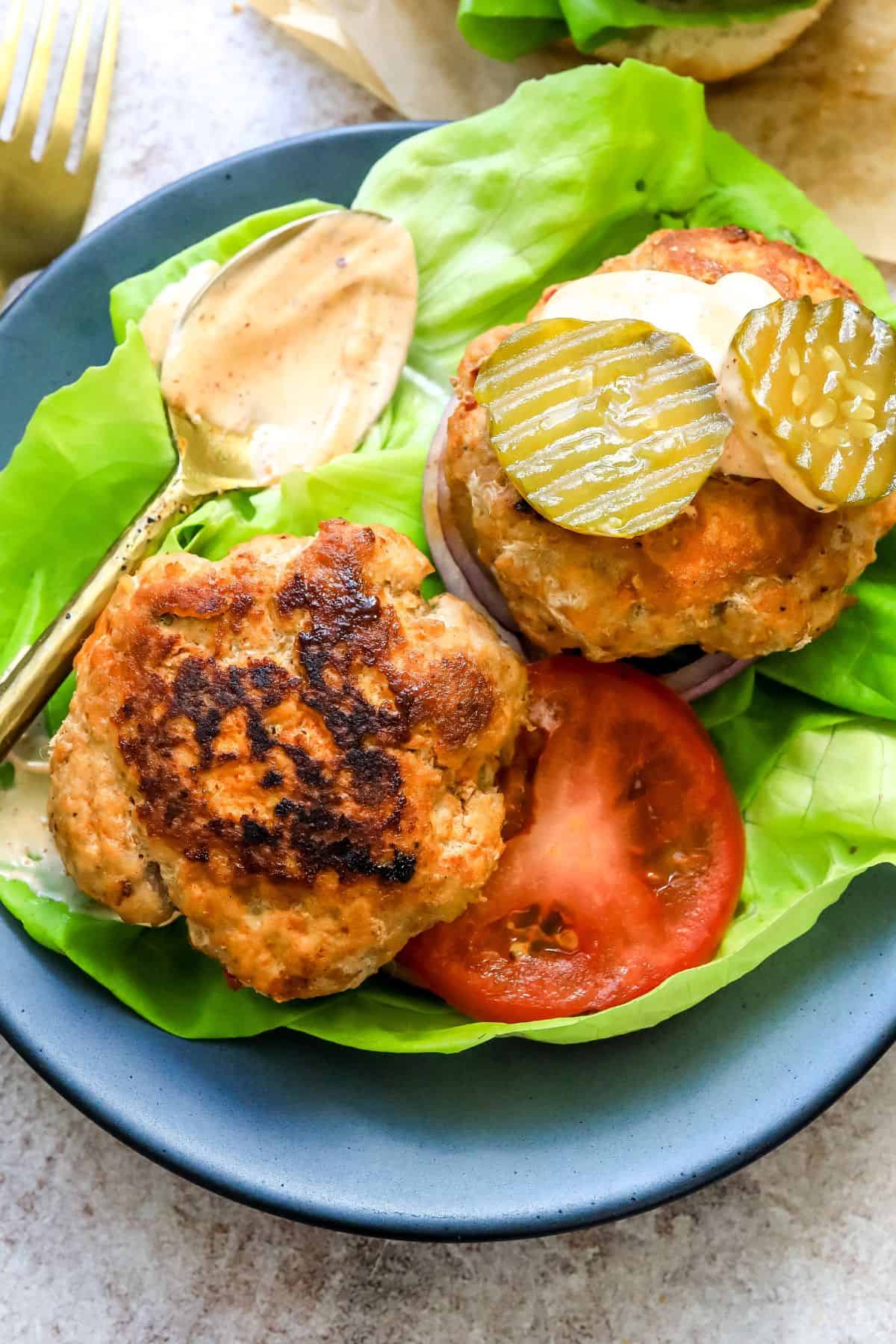 Spicy Chicken Burgers on lettuce wraps with pickles on top. 