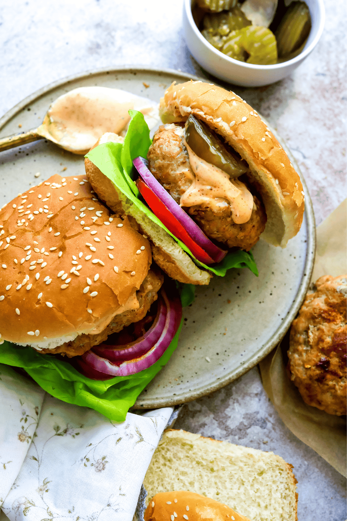 Air fryer spicy chicken burgers on a plate with a spoon of aioli to the side.
