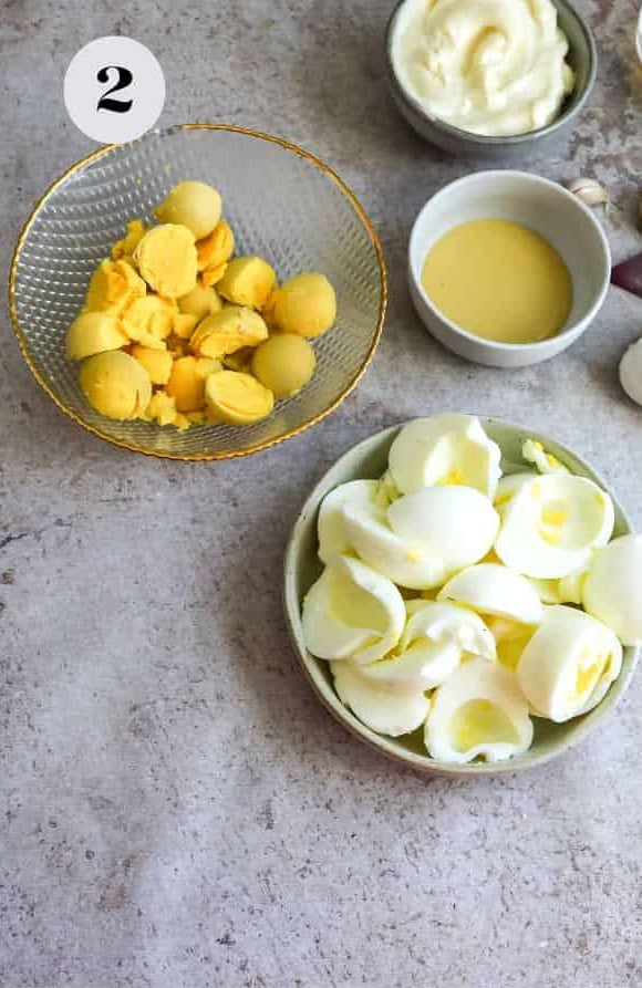 The egg yolks in a bowl and the egg whites in a separate bowl on a countertop.
