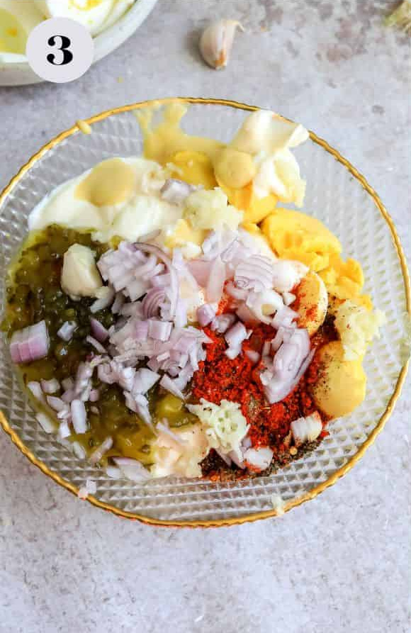 The mashed egg yolks, mayo, mustard, seasonings, and vinegar in a bowl before mixing together.