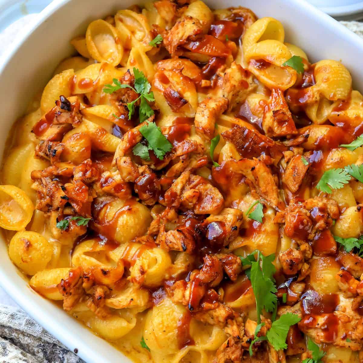 Close up of mac and cheese with bbq chicken mixed in in a white baking dish.