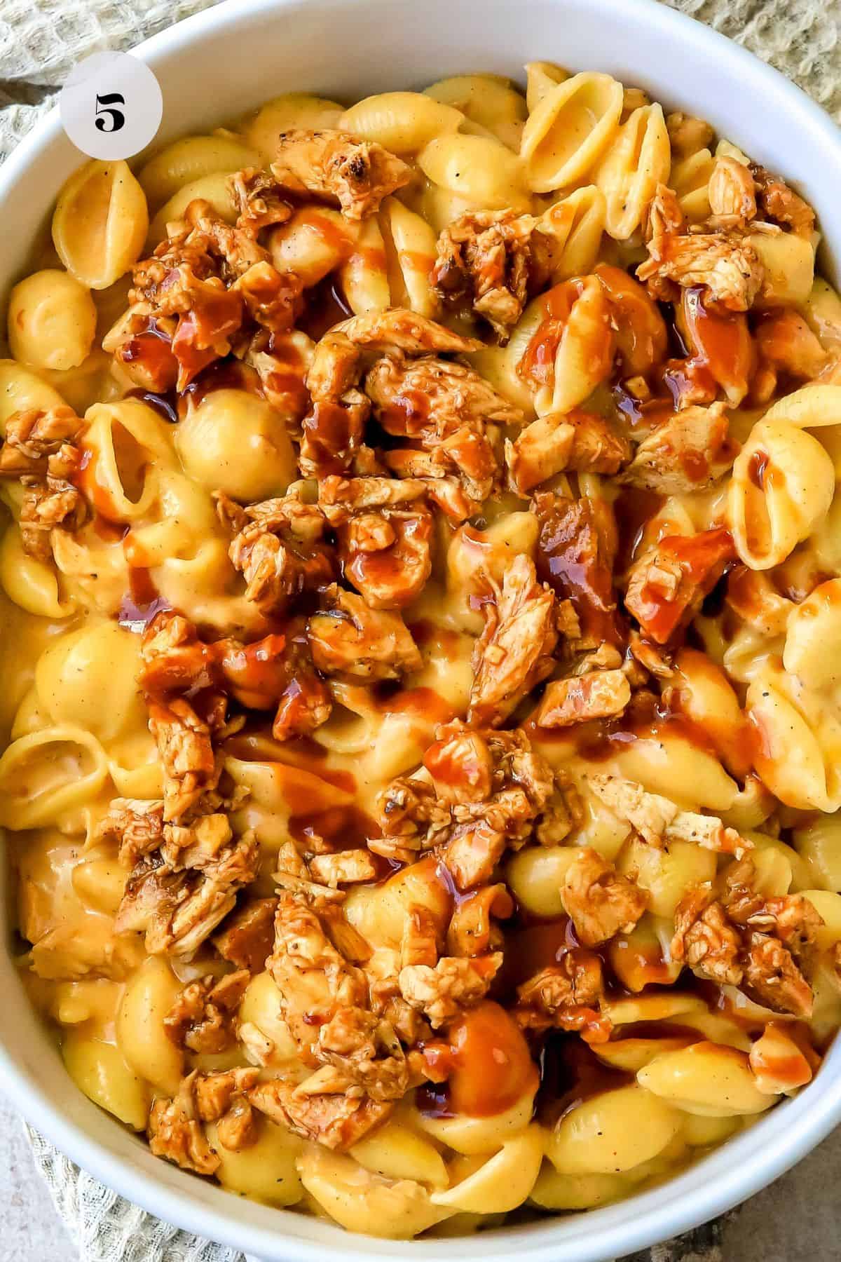 White dish with cheese shells and bbq chicken in it. 