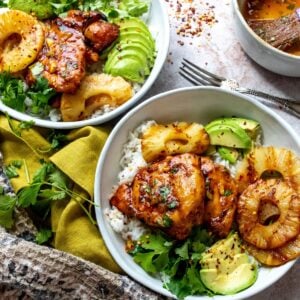 White ceramic bowls with juicy Hawaiian BBQ Chicken over rice and a fork to the side.