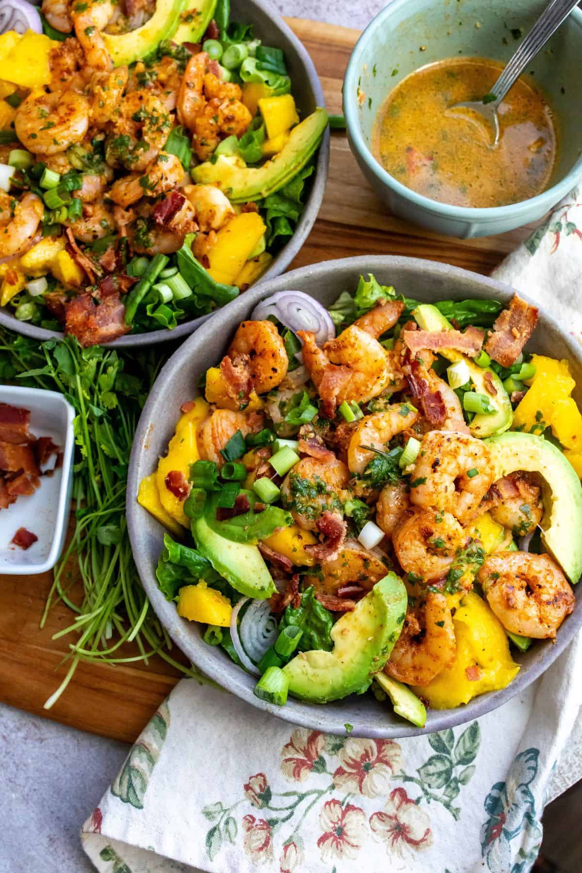 Grey bowl with mango, shrimp and salad in it. Cilantro to the side. 
