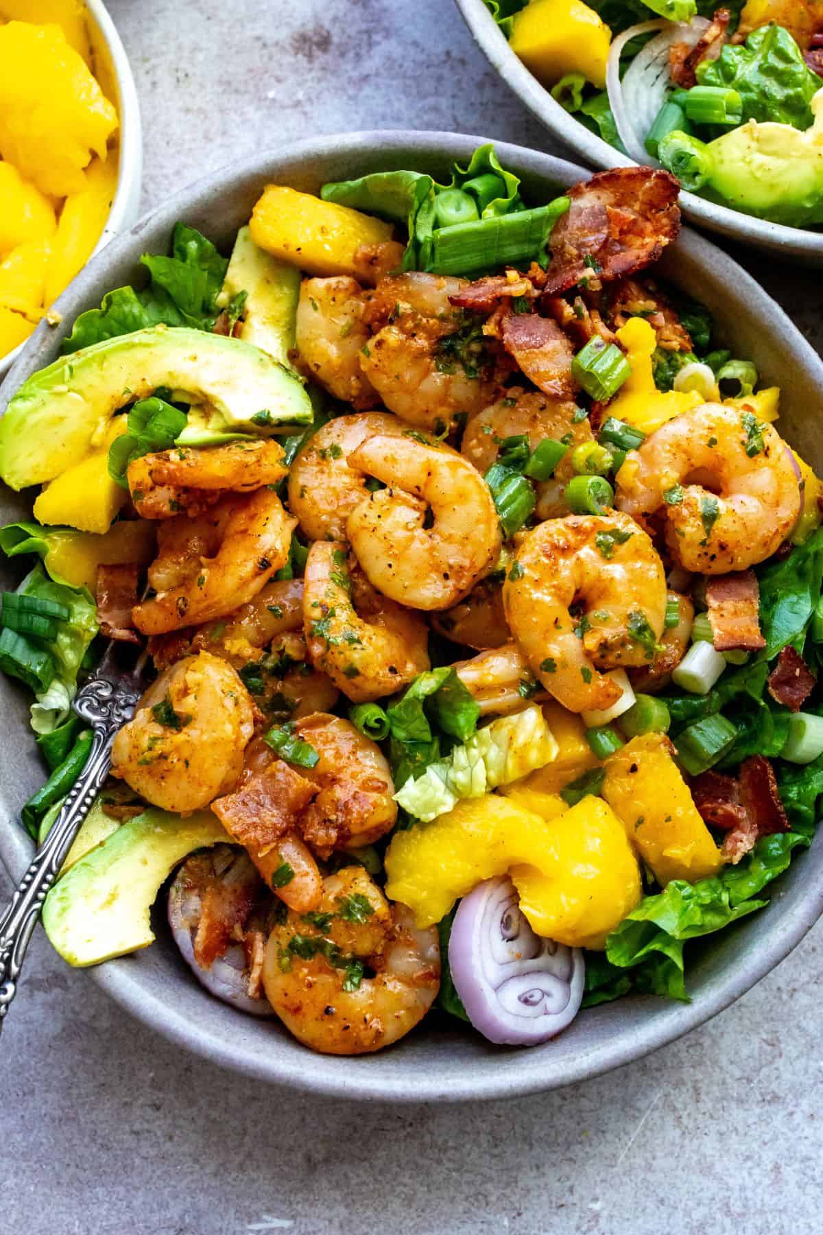 Grey bowl with mango, shrimp and salad in it. Cilantro to the side. 
