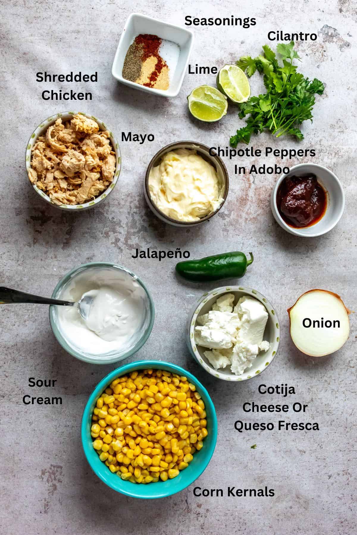 An overhead image of the ingredients of Mexican street corn casserole in separate containers with labels.