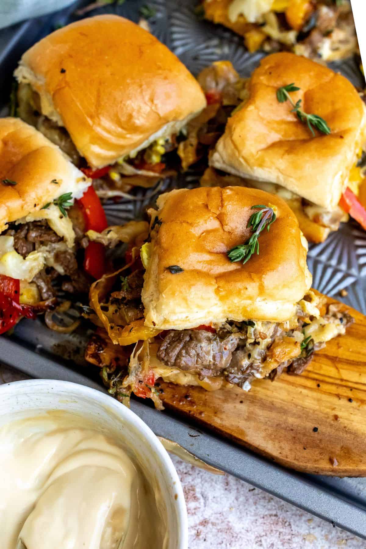 An overhead image of philly cheesesteak sliders on a serving plate.