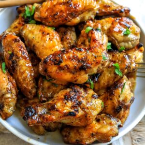 White ceramic bowl with sauce hot honey wings in it.