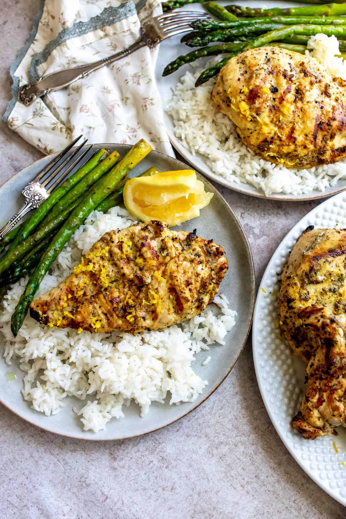 Grey plates with lemon pepper chicken on rice. Squeezed lemon on the side. 