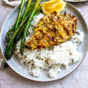 Grey plates with lemon pepper chicken on rice. Squeezed lemon on the side.