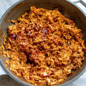 A close up image of shredded BBQ chicken in a skillet.