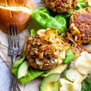 Up close photo of canned salmon burger with onions on top. A silver fork to the side.