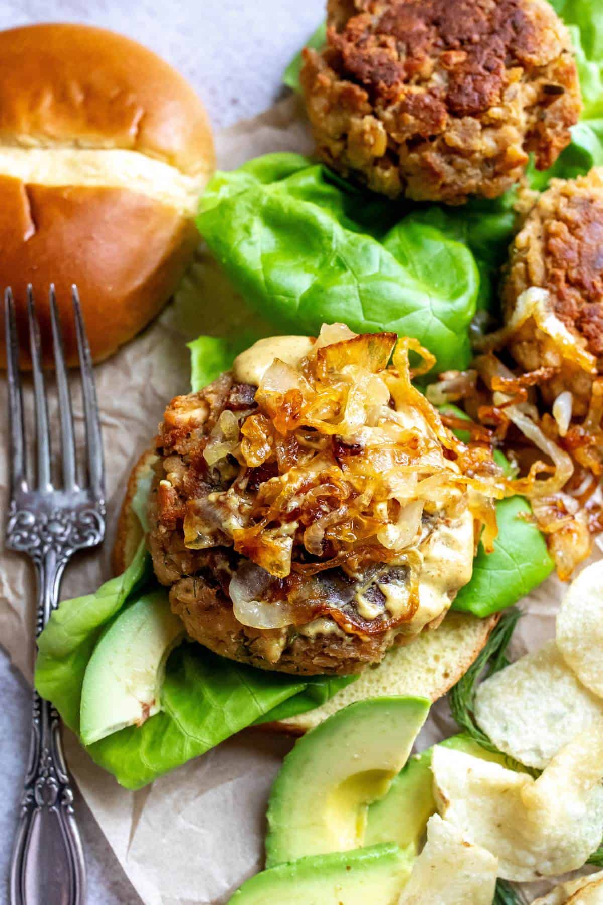 Up close photo of canned salmon burger with onions on top. A silver fork to the side.