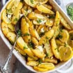 White ceramic dish with Lemon Roasted Potatoes in it and a grey towel underneath.