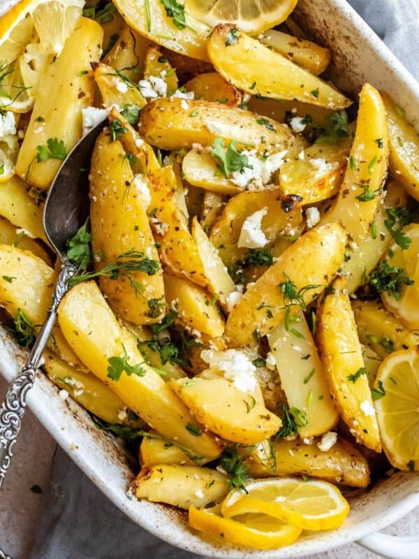 White ceramic dish with Lemon Roasted Potatoes in it and a grey towel underneath.