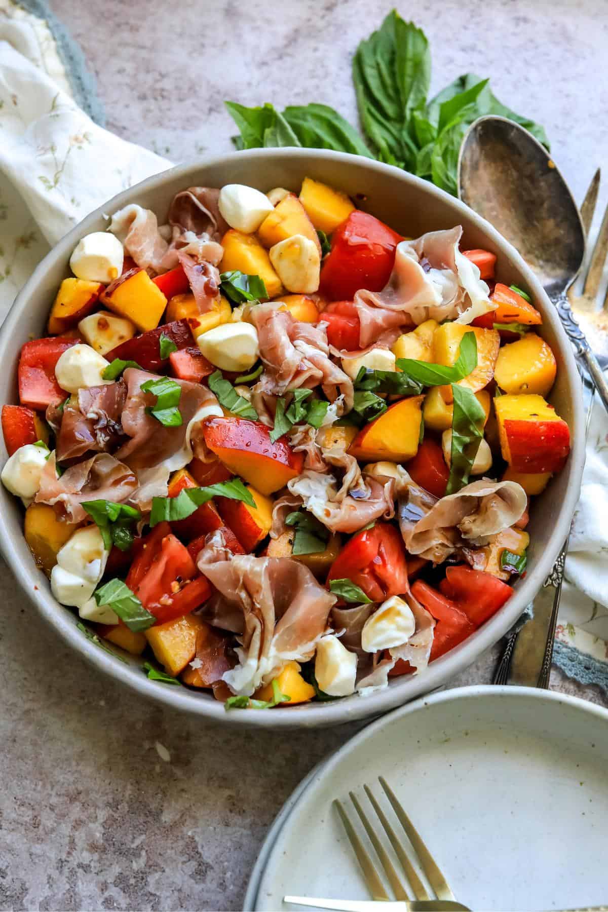 Overhead shot of peach caprese salad with basil and a spoon on the side.