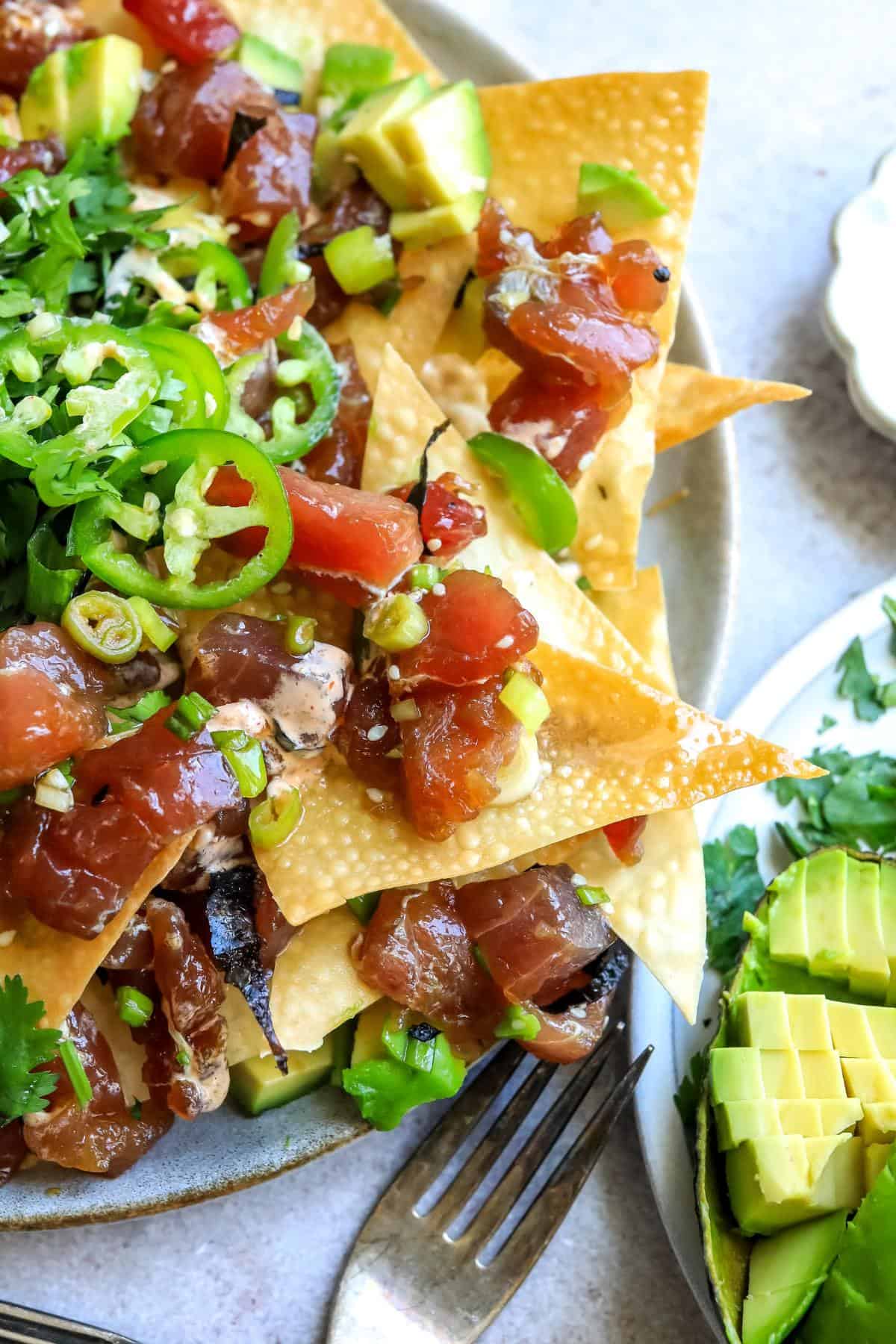 Poke Chip nachos on a plate with toppings. Up close photo.