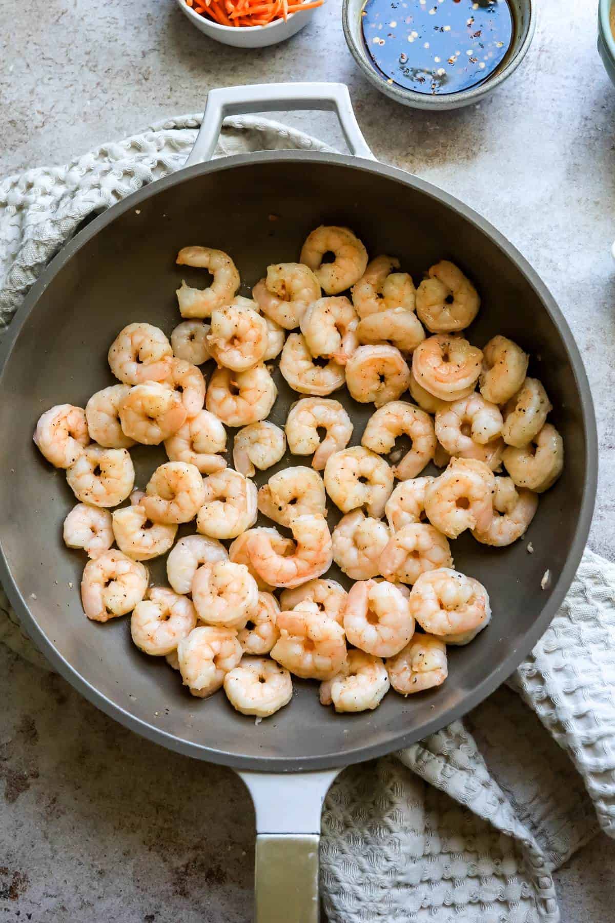 Grey skillet with cooked shrimp in it. 