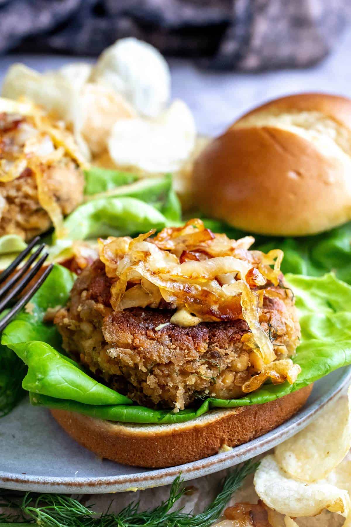 Up close photo of canned salmon burgers on a bun with a fork. 