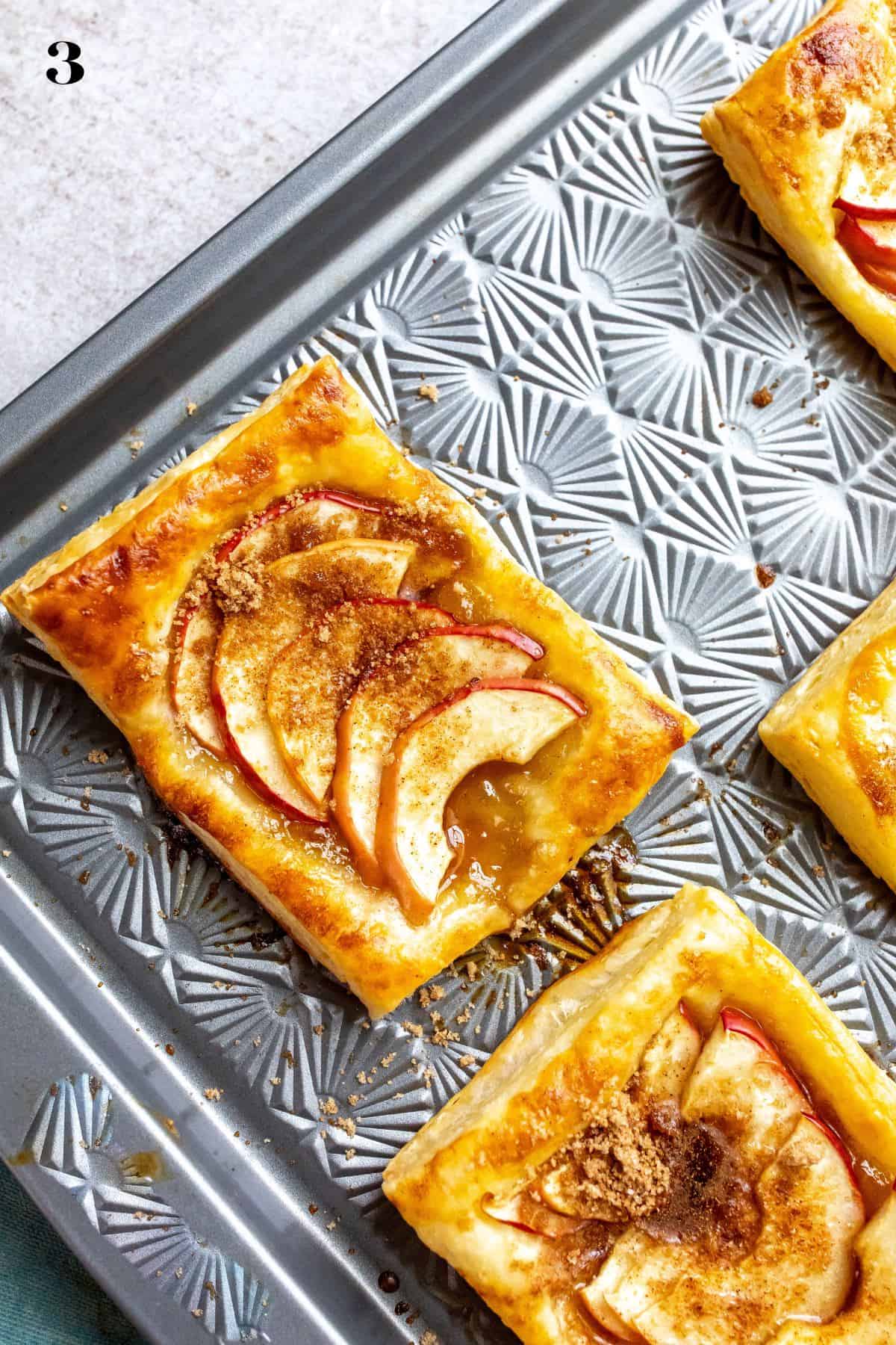 An image of baked apple tarts on a baking sheet.