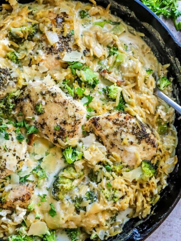 Cast iron pan with Baked Chicken Alfredo Orzo in it topped with parmesan.