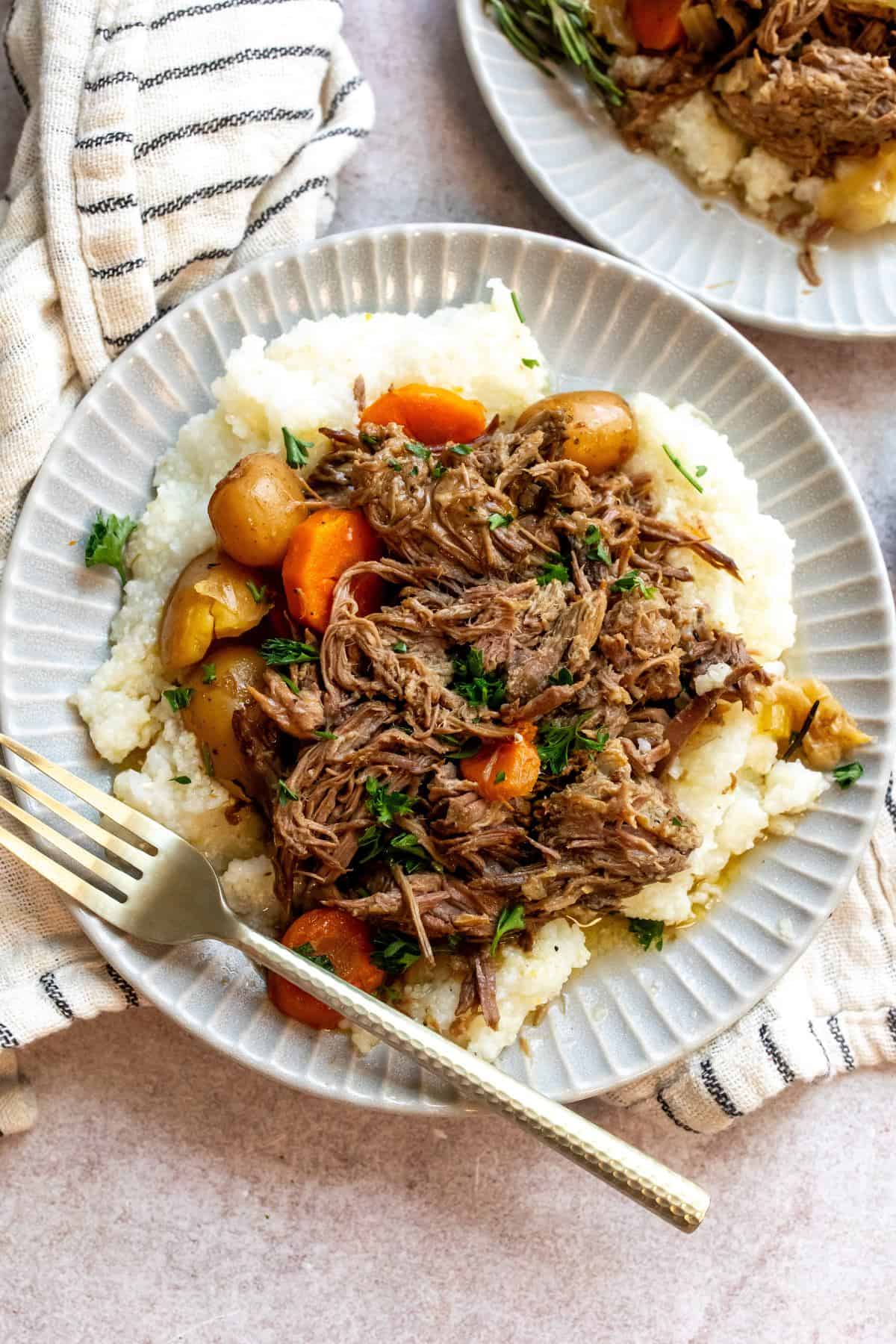 An overhead image beef chuck roast recipe with potatoes and carrots on a plate.