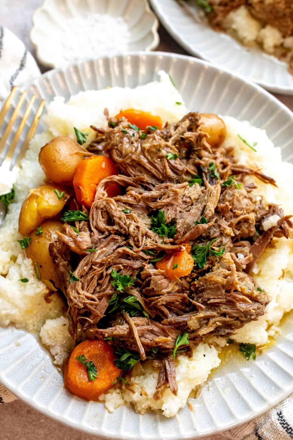 An overhead image beef chuck roast recipe with potatoes and carrots on a plate.