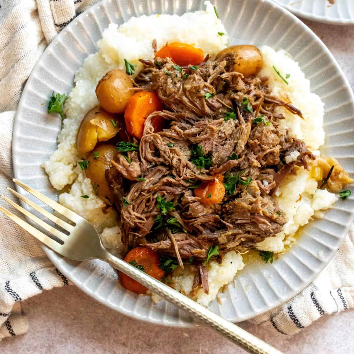 An overhead image beef chuck roast recipe with potatoes and carrots on a plate.